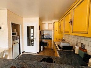 A kitchen with yellow cabinets, a microwave, and a sink. - 3-room apartment near the beach - 57m² (Argelès-sur-Mer)