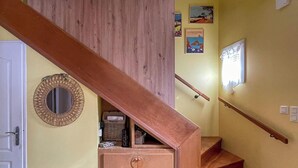 Eine Holztreppe mit Handlauf, eine Tür mit rundem Spiegel und ein kleiner Hocker.