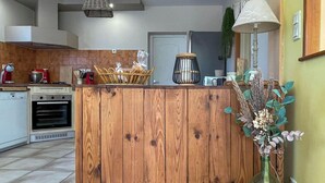 Eine Küche mit einer Holzinsel, einem roten Rührgerät, einem weißen Backofen und einem Korb mit Brot.