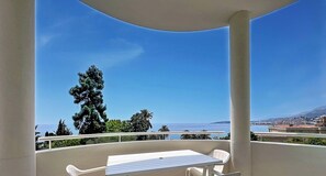 Ein Balkon mit Tisch und Stühlen, mit Blick auf eine Küstenstadt.