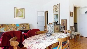 Un espace repas comprenant une table ronde, des chaises, un canapé et un buffet.
