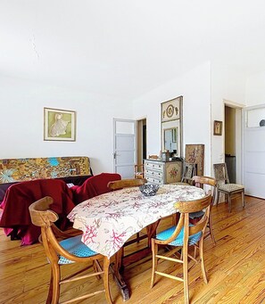 A dining area with a round table, chairs, a sofa, and a cabinet. - Charming apartment, sea view - 4 guests (Menton)
