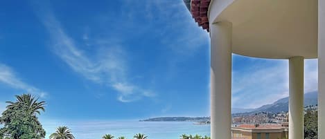 Un balcon offrant une vue dégagée sur la mer et le paysage urbain lointain.