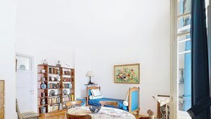 Une pièce comprenant un lit, une bibliothèque, une table avec un bol, une lampe et un tableau accroché au mur.