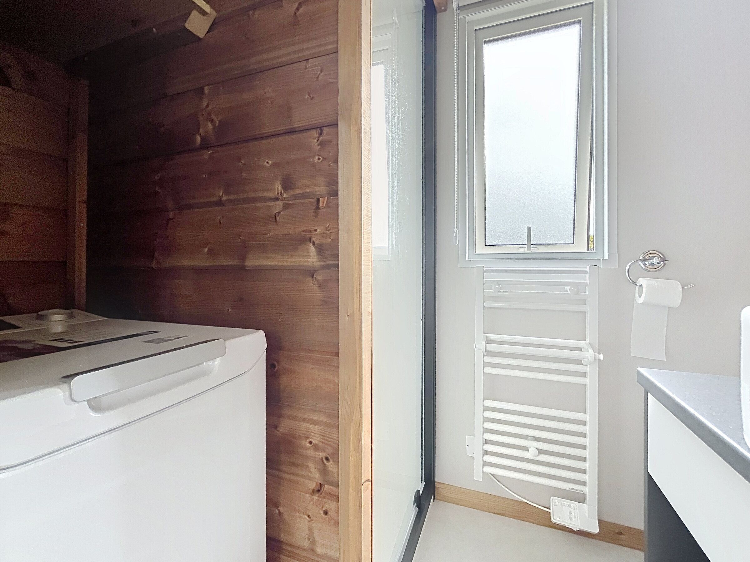 A room with a wooden wall, a white radiator, and a window.