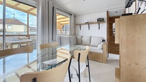 Ein zeitgemäßer Wohnraum mit einem Glastisch, Holzsesseln, einer Couch und Blick ins Freie.