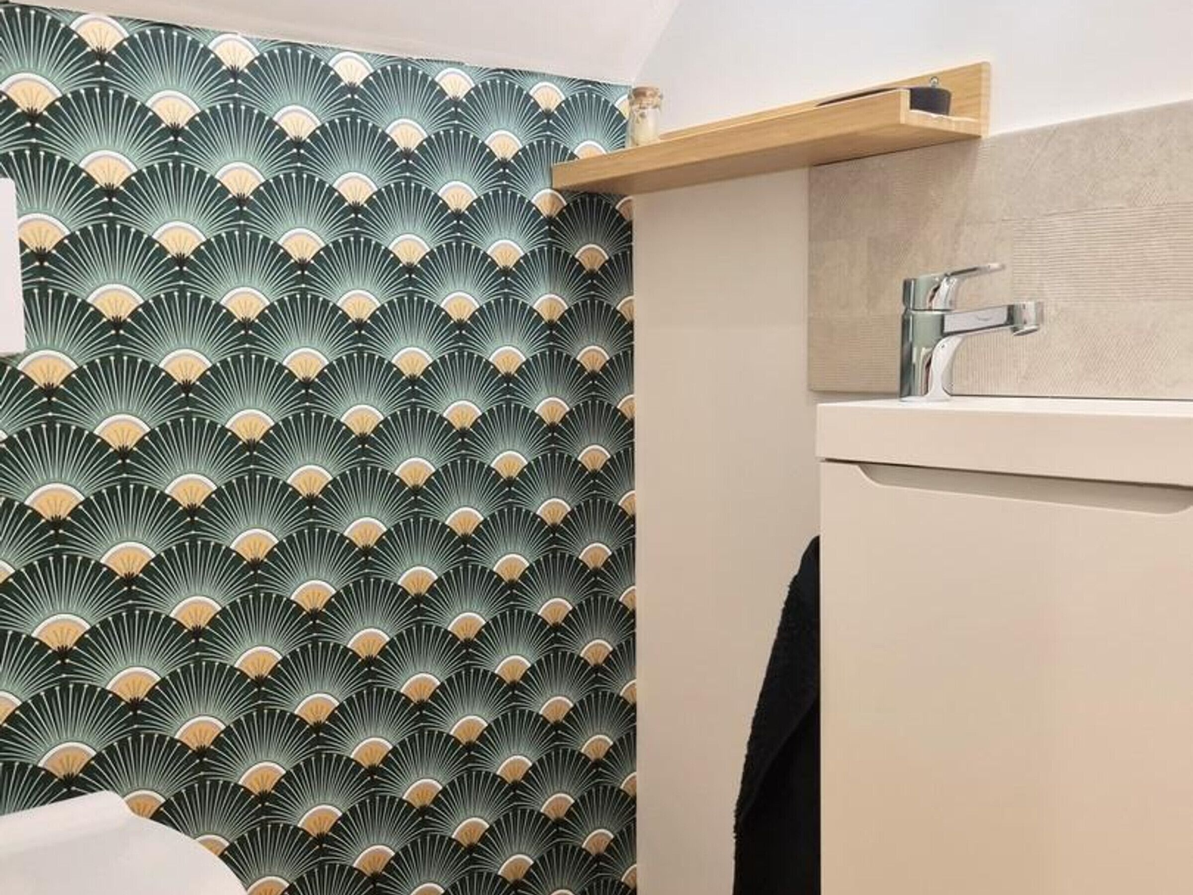 Un bagno con carta da parati decorata, uno scaffale in legno e un lavandino moderno.