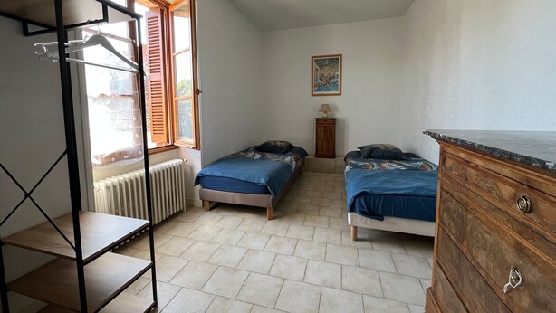 A bedroom with two beds, a radiator, a wooden dresser, and a shelf unit. - Quiet cottage, pets allowed, parking - 6 guests (Chambon)