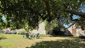 A grassy outdoor area with a stone building, a tree providing shade, and outdoor seating. - Quiet cottage, pets allowed, parking - 6 guests (Chambon)