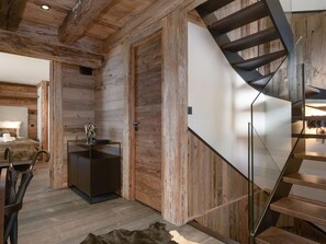 A modern interior with a wooden wall, a glass staircase, a kitchen area, and a bed. - Chalet in Courchevel 1850, 8 guests, ski-in/ski-out, sauna, Wifi (Courchevel)