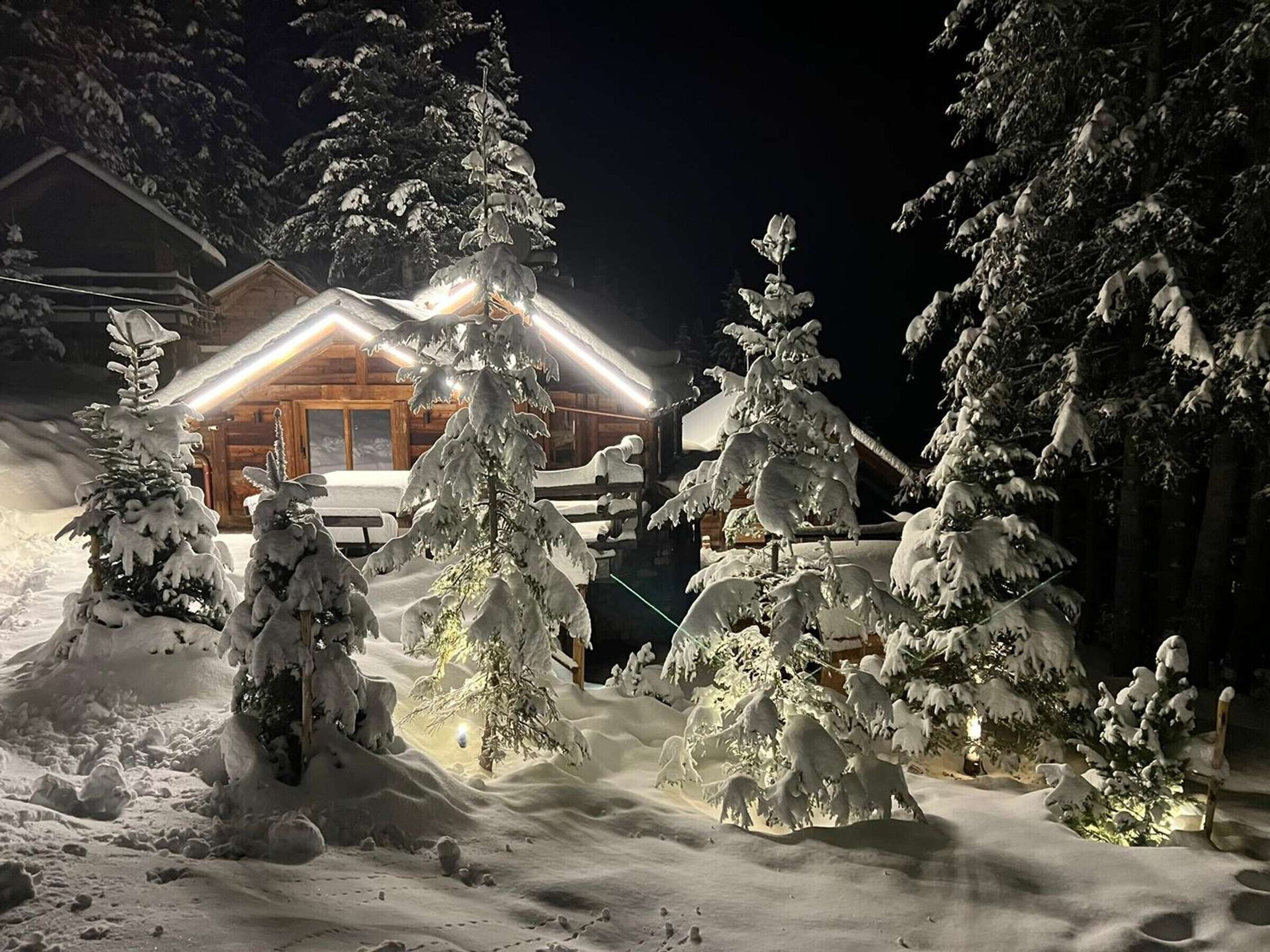 A snow-covered lodge with a wooden exterior and a lit entrance.