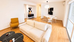 A modern living room with a sofa, a dining table, and a small coffee table. - Premium 3 Bd Retreat in Neapoli-Lycabettus (Athina)