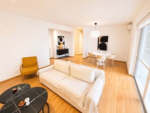 A modern living room with a sofa, a dining table, and a small coffee table. - Premium 3 Bd Retreat in Neapoli-Lycabettus (Athina)