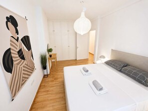 A bedroom with a bed, a bedside table, a hanging light fixture, a wardrobe, and a wall with a large abstract painting. - Premium 3 Bd Retreat in Neapoli-Lycabettus (Athina)