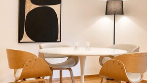 A modern dining area with a round table, four wooden chairs, a pendant light, a floor lamp, and a large abstract painting on the wall. - Premium 3 Bd Retreat in Neapoli-Lycabettus (Athina)