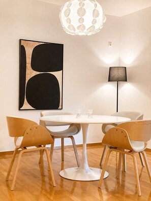 A modern dining area with a round table, four wooden chairs, a pendant light, a floor lamp, and a large abstract painting on the wall. - Premium 3 Bd Retreat in Neapoli-Lycabettus (Athina)