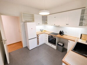 A compact kitchen with white cabinets, a built-in oven, a refrigerator, and a small countertop. - Premium 3 Bd Retreat in Neapoli-Lycabettus (Athina)