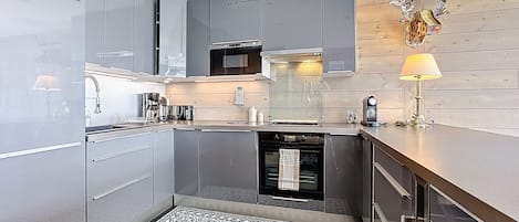 Une cuisine moderne avec des meubles gris, un four encastré et un tapis à motifs.