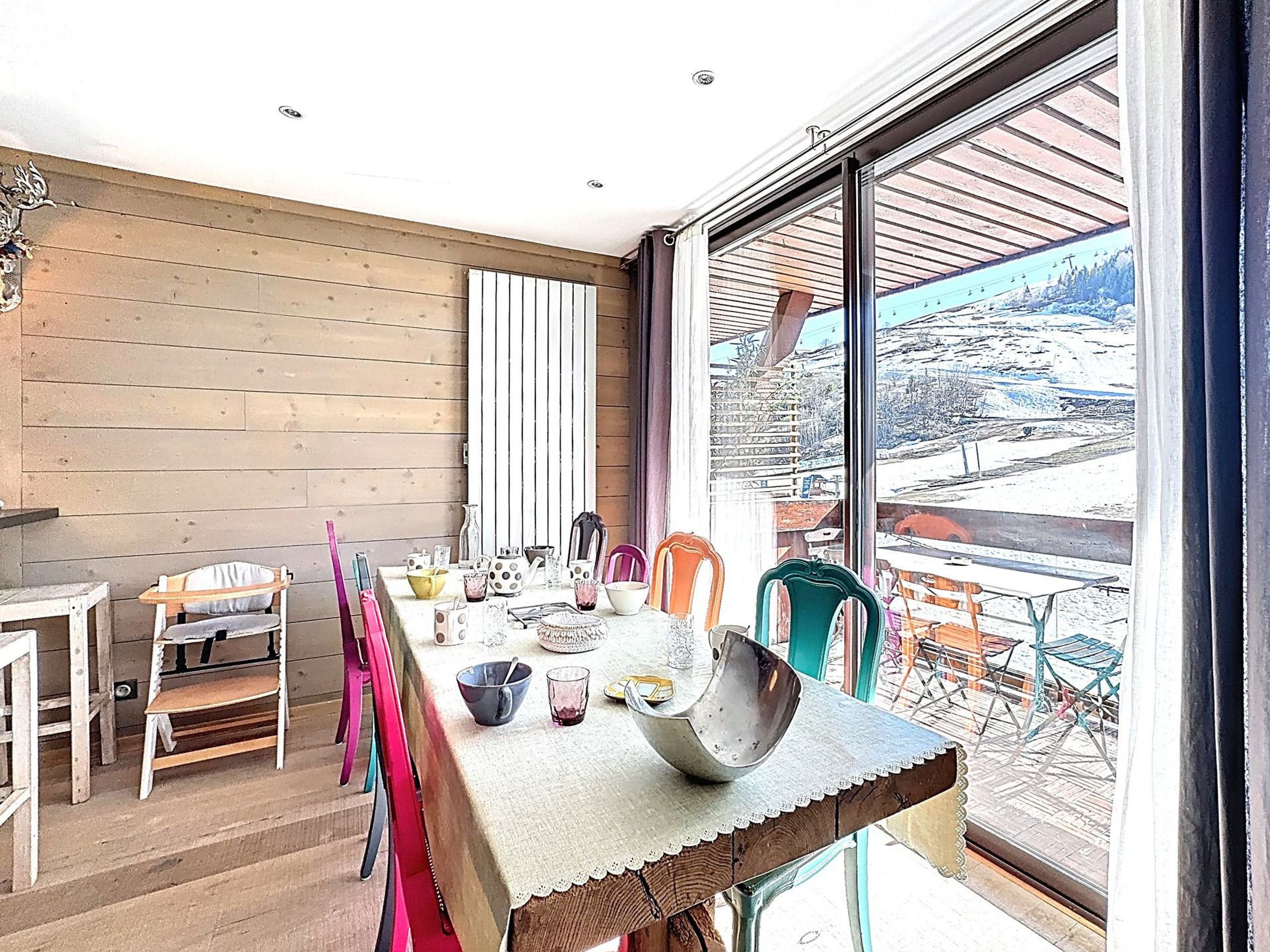 Un comedor con una mesa grande, sillas y vistas a un paisaje nevado a través de un ventanal.