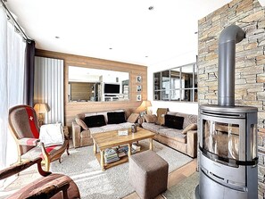 A cozy living room with a fireplace, a sofa set, a coffee table, and a wooden chair. - Spacious apartment, central location - 8 guests (Le Corbier)