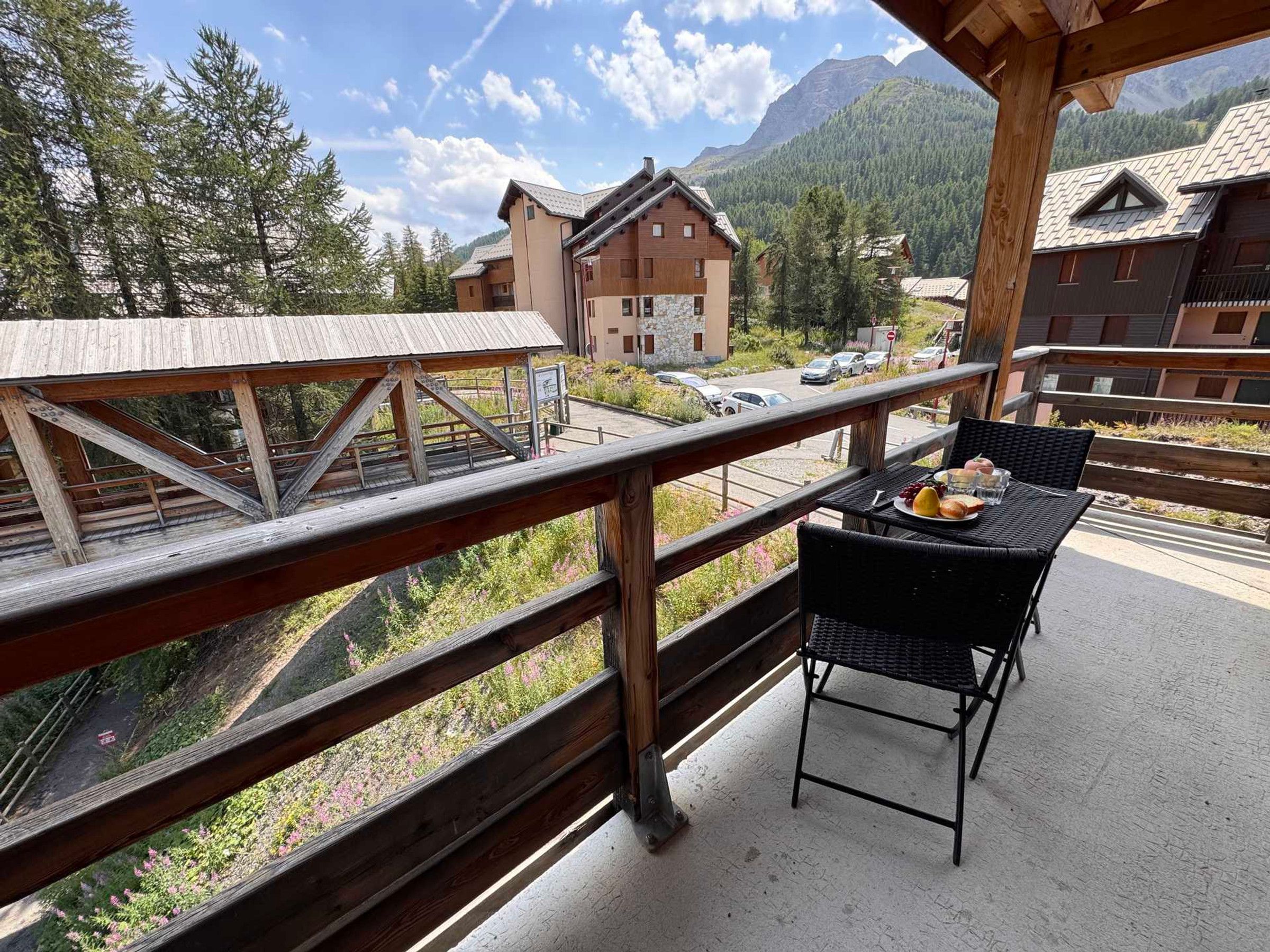 A balcony with a table set for dining, overlooking a mountainous landscape with traditional buildings.