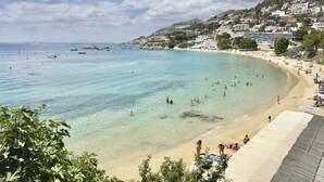 A coastal beach with clear waters, a sandy shore, and buildings on a hillside. - Air-conditioned apartment with beach access and terrace in Roses (Roses)
