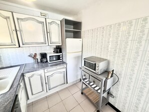 Uma cozinha compacta com armários brancos, micro-ondas, forno tostador e um pequeno balcão.