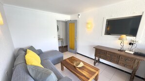 A living room with a sofa, a wooden coffee table, a TV mounted on the wall, and a small table with a lamp. - Air-conditioned apartment with beach access and terrace in Roses (Roses)
