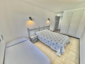 Um quarto com cama, mesas de cabeceira e guarda-roupa.