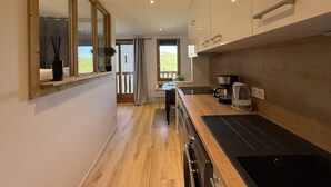 Eine moderne Küche mit einer Holz Arbeitsplatte, einem eingebauten Backofen und einem Fenster mit Blick auf einen Balkon.