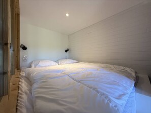 A bedroom with a large bed, two wall-mounted lights, and a wooden door. - Bright studio with unobstructed view - 4 guests (Belle Plagne)