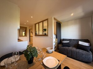 A modern living room with a sofa, a dining table set with plates and glasses, and a potted plant. - Bright studio with unobstructed view - 4 guests (Belle Plagne)