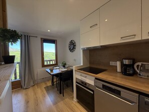A modern kitchen with a dining area, wooden flooring, and a view through a window. - Bright studio with unobstructed view - 4 guests (Belle Plagne)