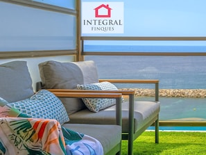 A balcony with a sofa, pillows, and a view of the sea. - Modern apartment, bay view - 4 guests (San Antonio de Calonge)