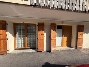 A building with a covered entrance, wooden doors, and a window with a curtain. - T3 Apartment in Les Gets, parking - 4 guests (Les Gets)