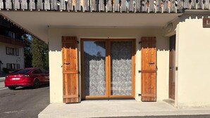 A building with a double door entrance, a red car parked in front, and a clear sky. - T3 Apartment, pets welcome - 74260 Les Gets (Les Gets)