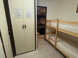 Ein Zimmer mit einem Etagenbett, einem Schrank mit zwei Türen und zwei Hinweisen an den Schranktüren.