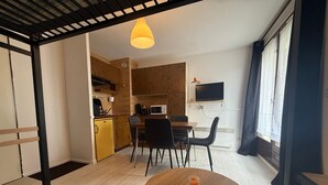 A compact living space with a dining area, kitchenette, and a TV mounted on the wall. - Studio cabin with mountain view - 4 guests (Les Adrets-Prapoutel)