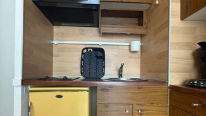 A compact kitchen with a built-in microwave, a small refrigerator, and wooden cabinetry. - Studio cabin with mountain view - 4 guests (Les Adrets-Prapoutel)