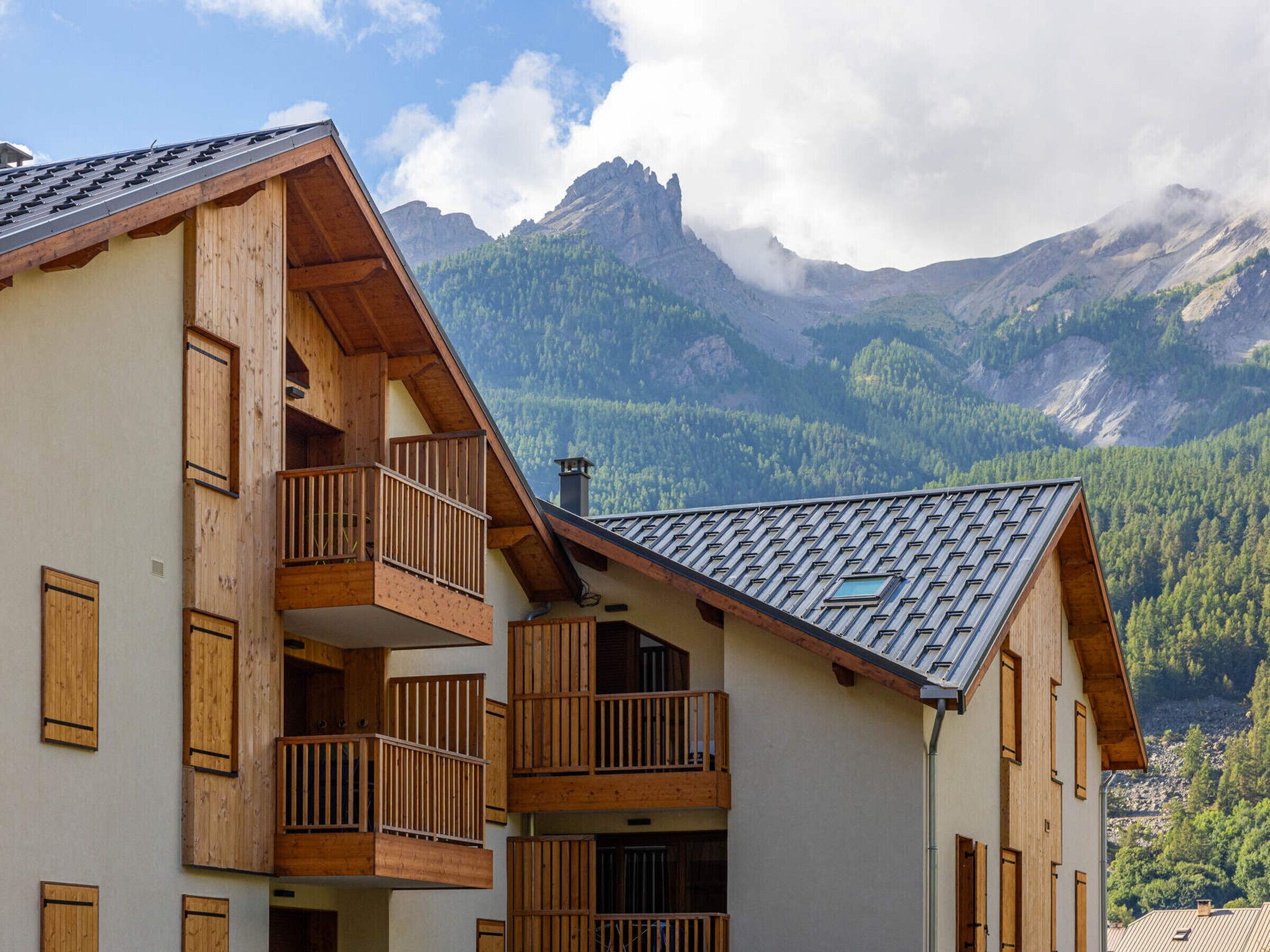 Un edificio de madera de varios pisos con balcones, con montañas al fondo.