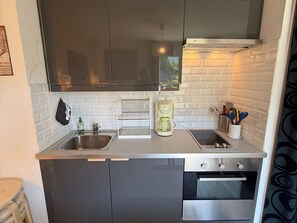 Eine kleine Küche mit einem doppelten Spülbecken, einer Kaffeemaschine und einem eingebauten Backofen.