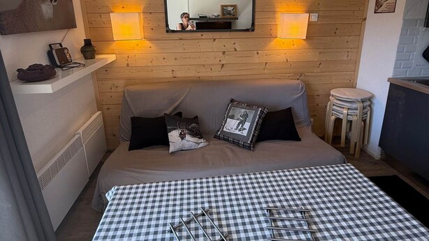 Een knus ingerichte kamer met een bed, een spiegel, twee wandlampen, een klein tafeltje en een radiator.