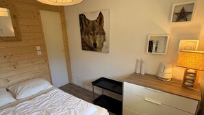Hotelkamer met een bed, een bureau, een lamp en een aan de muur bevestigd beeld van een wolf.