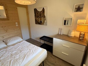 Ein Hotelzimmer mit einem Bett, einem Schreibtisch, einer Lampe und einem an der Wand hängenden Bild eines Wolfes.