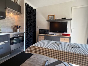 Eine kompakte Küche mit Mikrowelle, Backofen und einer kleinen Essecke mit kariertem Tischdecken.