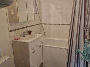 Ein Badezimmer mit weißem Waschbecken, Spiegel und Badewanne.