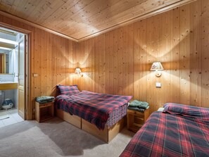 A room with wooden walls and a bed with a plaid bedspread. There are two bedside tables with lamps. - Spacious apartment pets OK, mountain view - 8 guests (Méribel)