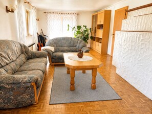 A living room with a sofa, a wooden table with a vase, and a potted plant.