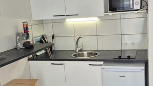 A compact kitchen with a microwave, sink, and dishwasher.