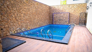 En rektangulär swimmingpool omgiven av en mur av sten.